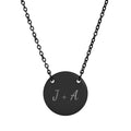 Black necklace with a round pendant featuring 'J + A' on a white background